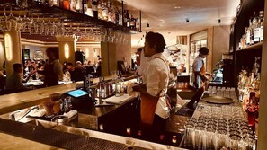A bar area with a bartender, shelves with bottles, and a dining area with patrons. - Cosy Darling Point apartment (Darling Point)