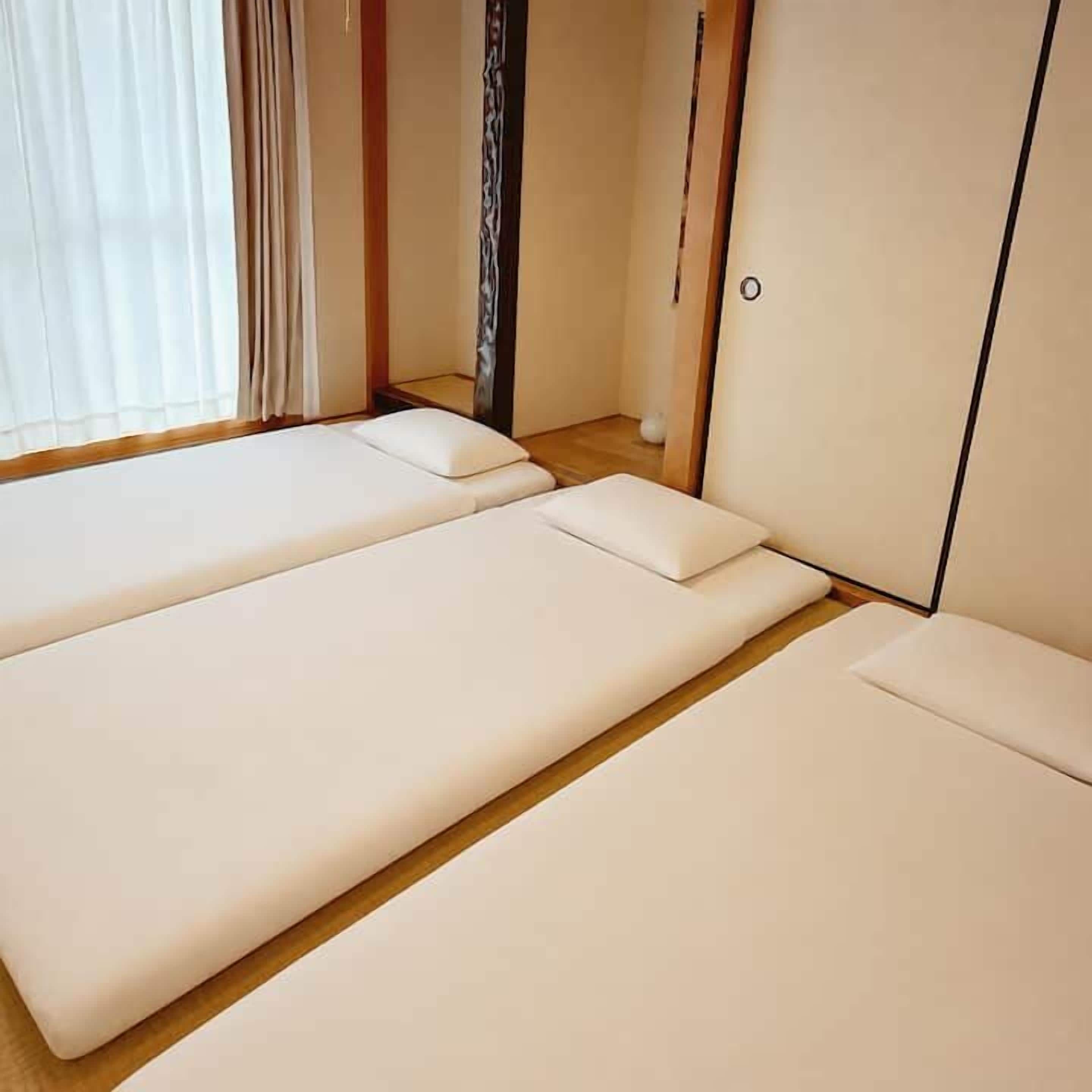 Een kamer met twee bedden, een houten vloer en een raam met gordijnen.