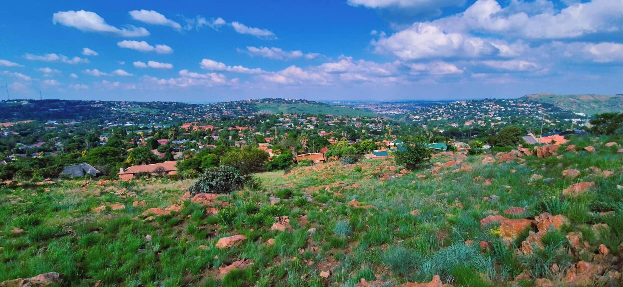 A rural landscape with scattered houses, green vegetation, and a clear sky.