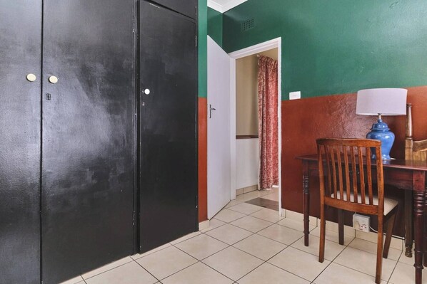 A room with a black door, a wooden chair, a desk with a lamp, and a curtain.