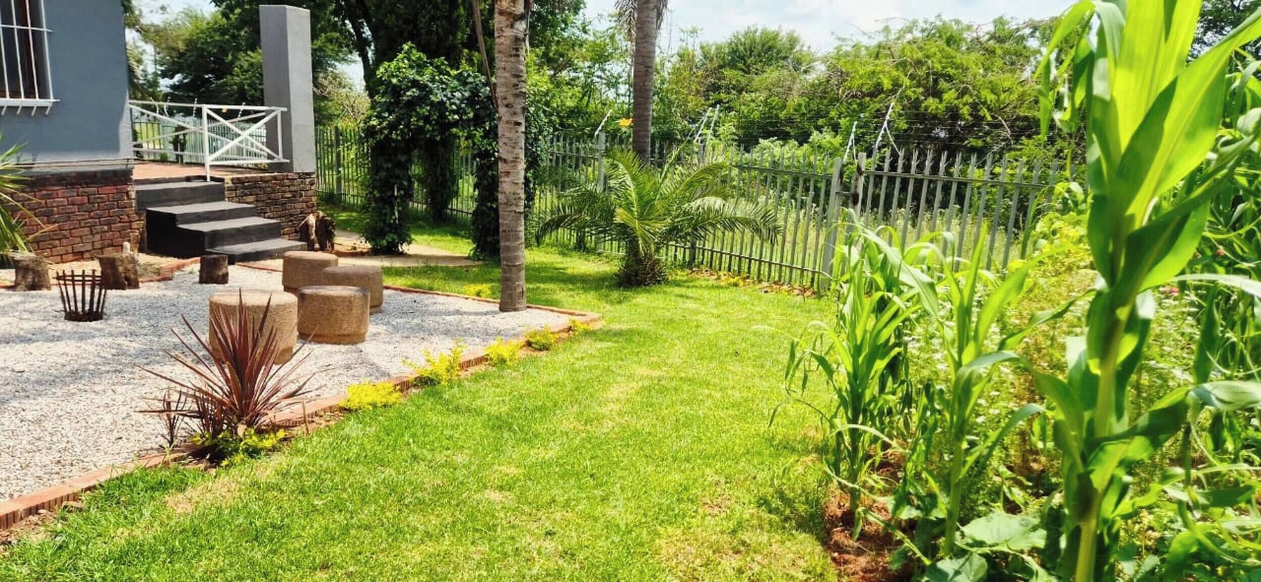 A well-maintained garden with a paved patio, outdoor seating, and a fenced area.