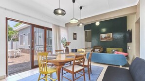A dining area with a wooden table and chairs, a sofa, and a TV mounted on the wall.