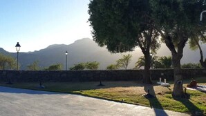 Piscina com montanhas ao fundo, paredes de pedra e árvores.