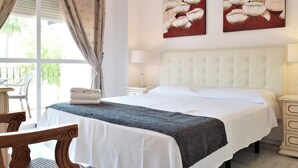 A bedroom with a bed, a chair, a nightstand, and a window with curtains. - Villa Anna - 4 Bedrooms F-3 (Marbella)