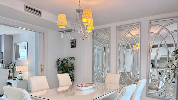 A modern dining area with a glass table, white chairs, and a chandelier. - Villa Anna - 4 Bedrooms F-3 (Marbella)