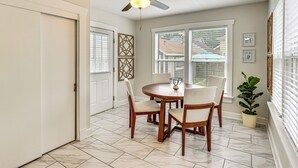 Un coin repas comprenant une table ronde, quatre chaises, un ventilateur de plafond et une plante en pot.