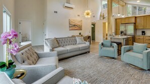 A spacious living area with a sofa, armchairs, a coffee table, and a dining area with a kitchen in the background. - Margaritaville Access! Luxe Ozark Oasis w/ Hot Tub (Osage Beach)