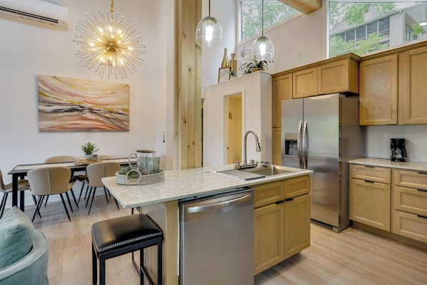 A modern kitchen with a central island, stainless steel appliances, wooden cabinets, and pendant lighting. - Margaritaville Access! Luxe Ozark Oasis w/ Hot Tub (Osage Beach)