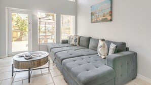 Uma sala de estar moderna com um sofá modular cinza, uma mesa de centro redonda e um quadro na parede.