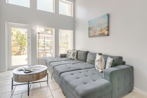 A modern living room with a grey sectional sofa, a round coffee table, and a painting on the wall. - Beach Days, Family Fun! Resort-Style Galveston Gem (Galveston)