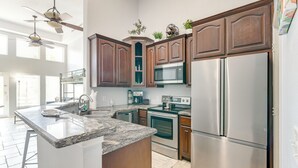 Cozinha moderna com bancadas de granito, eletrodomésticos de aço inoxidável e armários de madeira.