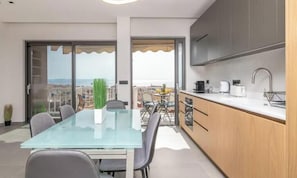 Eine moderne Küche mit Glastisch, Blick auf die Stadt und einem Balkon mit Tisch und Stühlen.