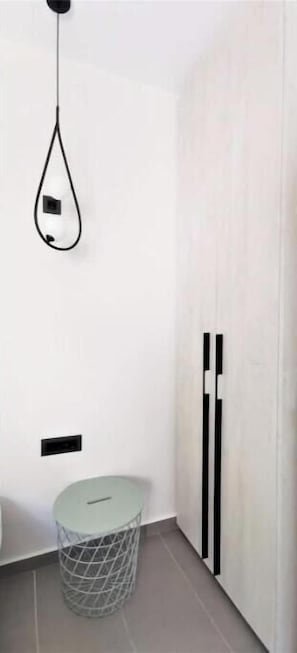 Ein modernes Badezimmer mit einer hängenden Leuchte, einem runden Mülleimer und einem vertikalen Heizkörper.