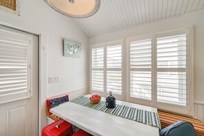 Una habitació amb una taula, una panxa, una finestra amb persianes, una porta i un llum fixat a la paret.
