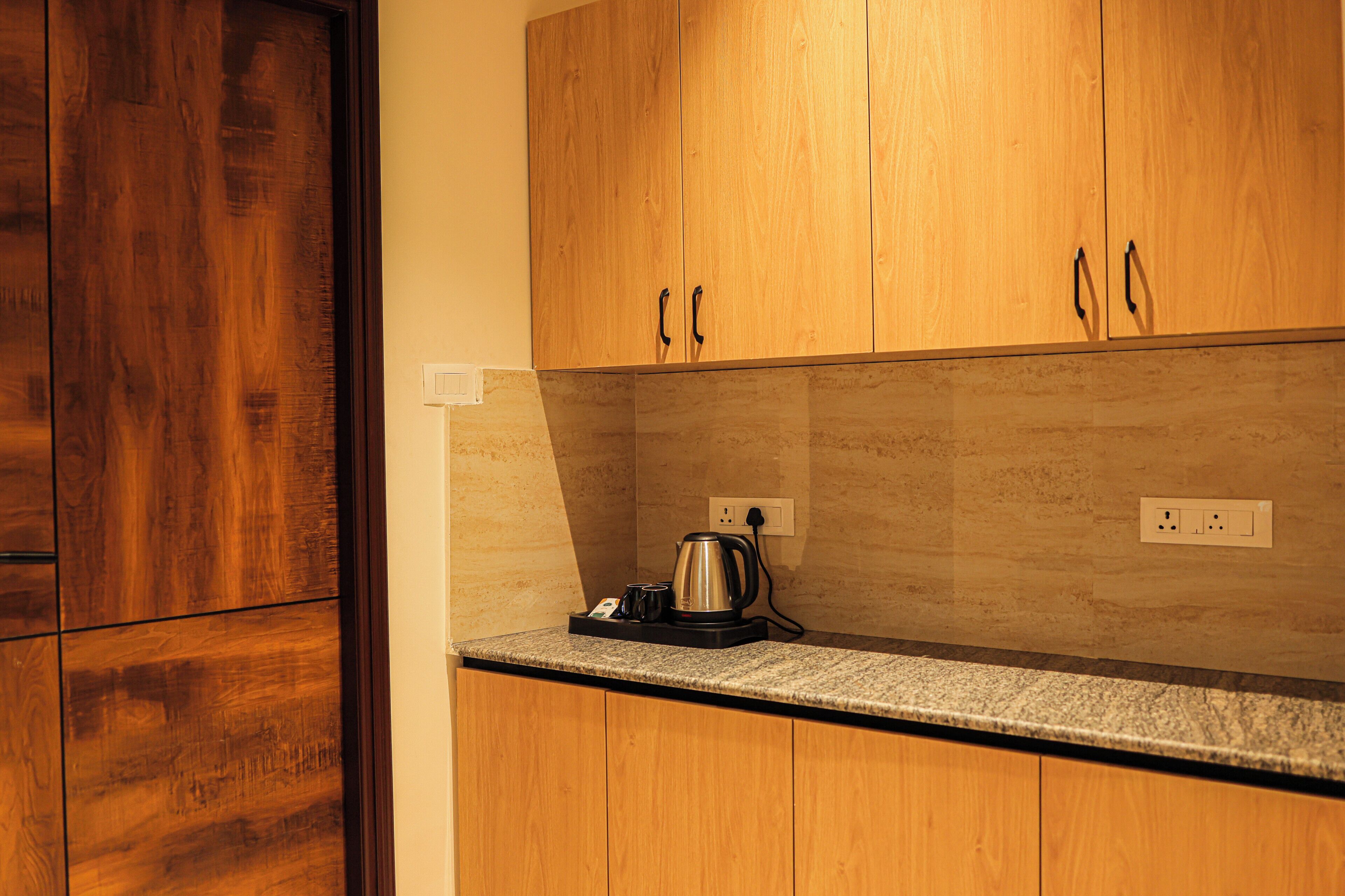 A kitchen with wooden cabinets, a granite countertop, and a kettle.
