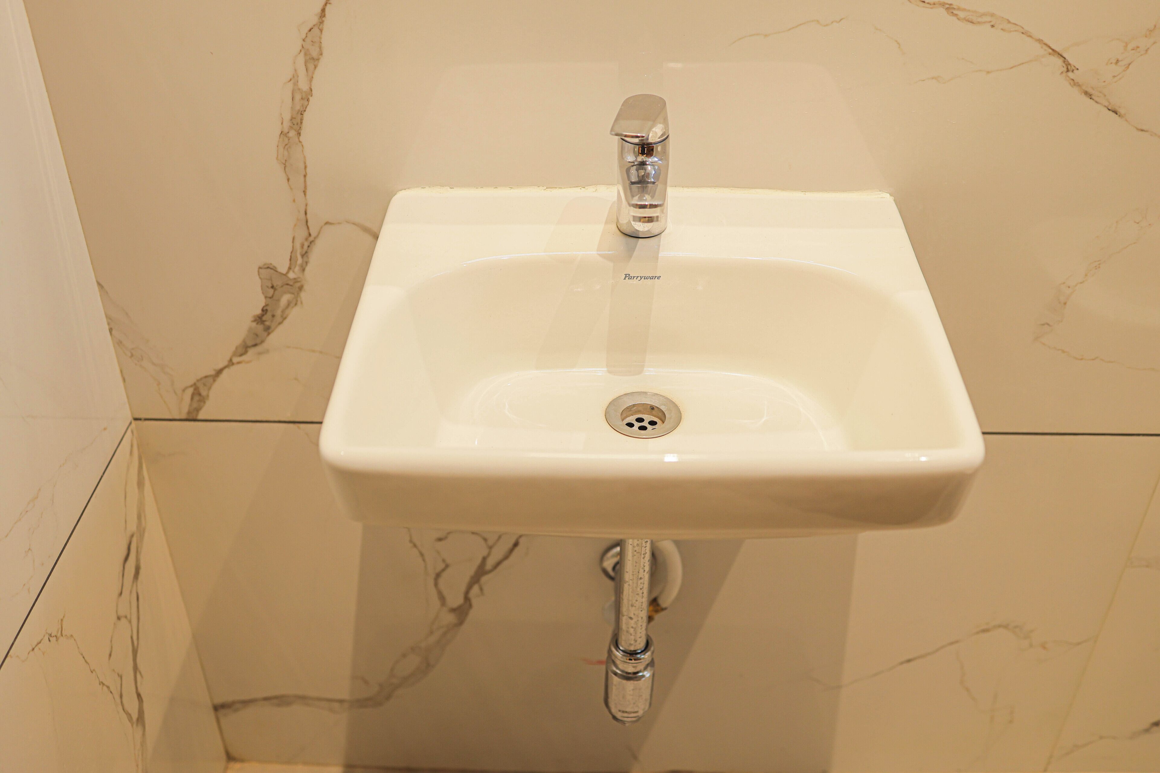 A bathroom sink with a marble backsplash and a single faucet.