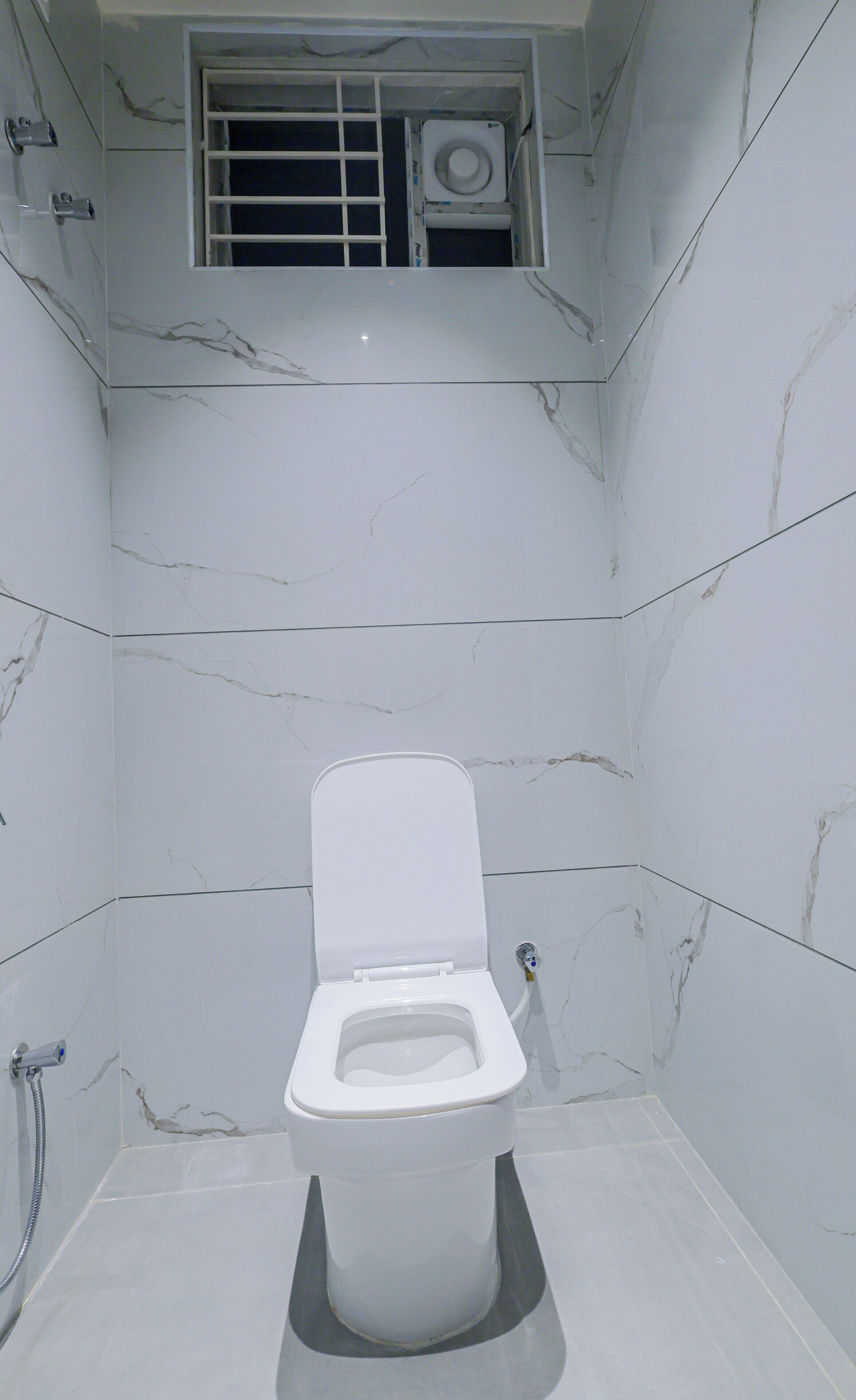 A bathroom with a toilet, a shower, and a window with a vent.