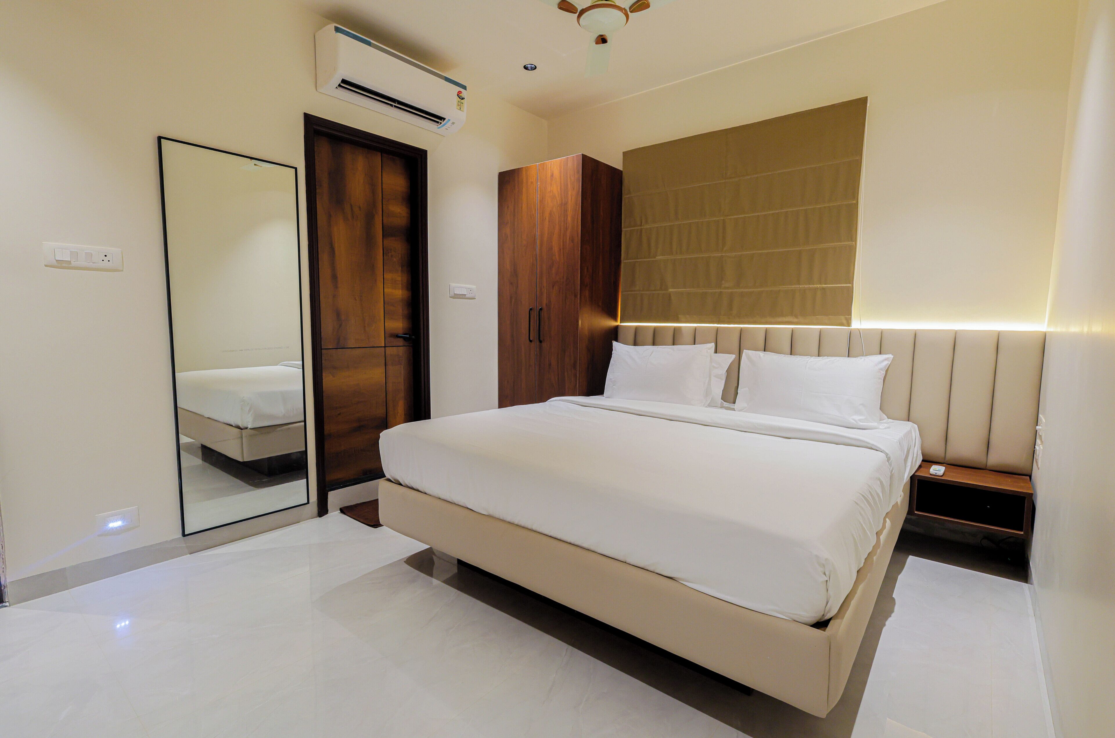 Une chambre d’hôtel moderne équipée d’un grand lit, d’une armoire, d’un miroir et d’une table de chevet.
