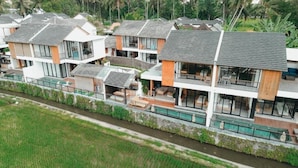 A modern residential complex with multiple two-story houses, each featuring large windows, outdoor seating areas, and a central courtyard. - Paz Tropical Villa Ubud (Ubud)
