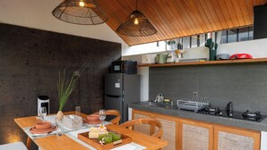 A modern kitchen with a wooden table, a built-in stove, and a refrigerator. - Paz Tropical Villa Ubud (Ubud)