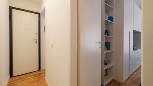 A hallway with a closed door, a white closet with shelves, and a wooden floor. - A comfortable and charming 40 square meters apartment, perfect for three people, located on the second floor of a period building with an elevator (NOT accessible to disabled guests).The property is located near Rome Termini Station and the Castro Pretor (Rome)