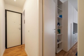 A hallway with a closed door, a white closet with shelves, and a wooden floor. - A comfortable and charming 40 square meters apartment, perfect for three people, located on the second floor of a period building with an elevator (NOT accessible to disabled guests).The property is located near Rome Termini Station and the Castro Pretor (Rome)