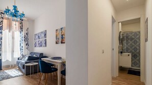A modern living room with a sofa, dining table, chairs, and artwork on the walls. - A comfortable and charming 40 square meters apartment, perfect for three people, located on the second floor of a period building with an elevator (NOT accessible to disabled guests).The property is located near Rome Termini Station and the Castro Pretor (Rome)