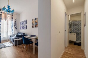 A modern living room with a sofa, dining table, chairs, and artwork on the walls. - A comfortable and charming 40 square meters apartment, perfect for three people, located on the second floor of a period building with an elevator (NOT accessible to disabled guests).The property is located near Rome Termini Station and the Castro Pretor (Rome)