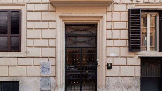 A building facade with a central entrance, a window with shutters, and a door with a metal grille. - A comfortable and charming 40 square meters apartment, perfect for three people, located on the second floor of a period building with an elevator (NOT accessible to disabled guests).The property is located near Rome Termini Station and the Castro Pretor (Rome)