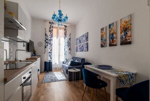 A modern kitchen with a dining area, a sofa, and artwork on the walls. - A comfortable and charming 40 square meters apartment, perfect for three people, located on the second floor of a period building with an elevator (NOT accessible to disabled guests).The property is located near Rome Termini Station and the Castro Pretor (Rome)