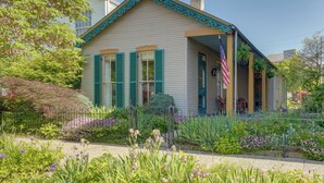 Une maison à deux étages avec un porche, un drapeau et un jardin.