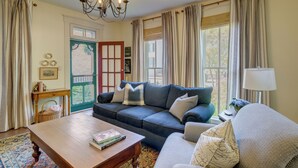 Un salon avec un canapé, une table basse, une lampe et une fenêtre avec des rideaux.
