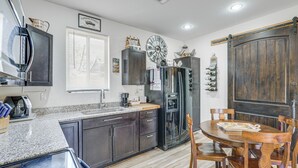 A kitchen with dark cabinets, a refrigerator, a clock, and a dining table with chairs. - Private Acreage, Pet-Friendly Yard! Gilbert Haven (Gilbert)