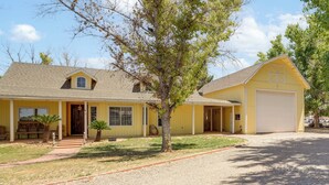 A yellow two-story house with a garage, a front porch, and a tree in the yard. - Private Acreage, Pet-Friendly Yard! Gilbert Haven (Gilbert)