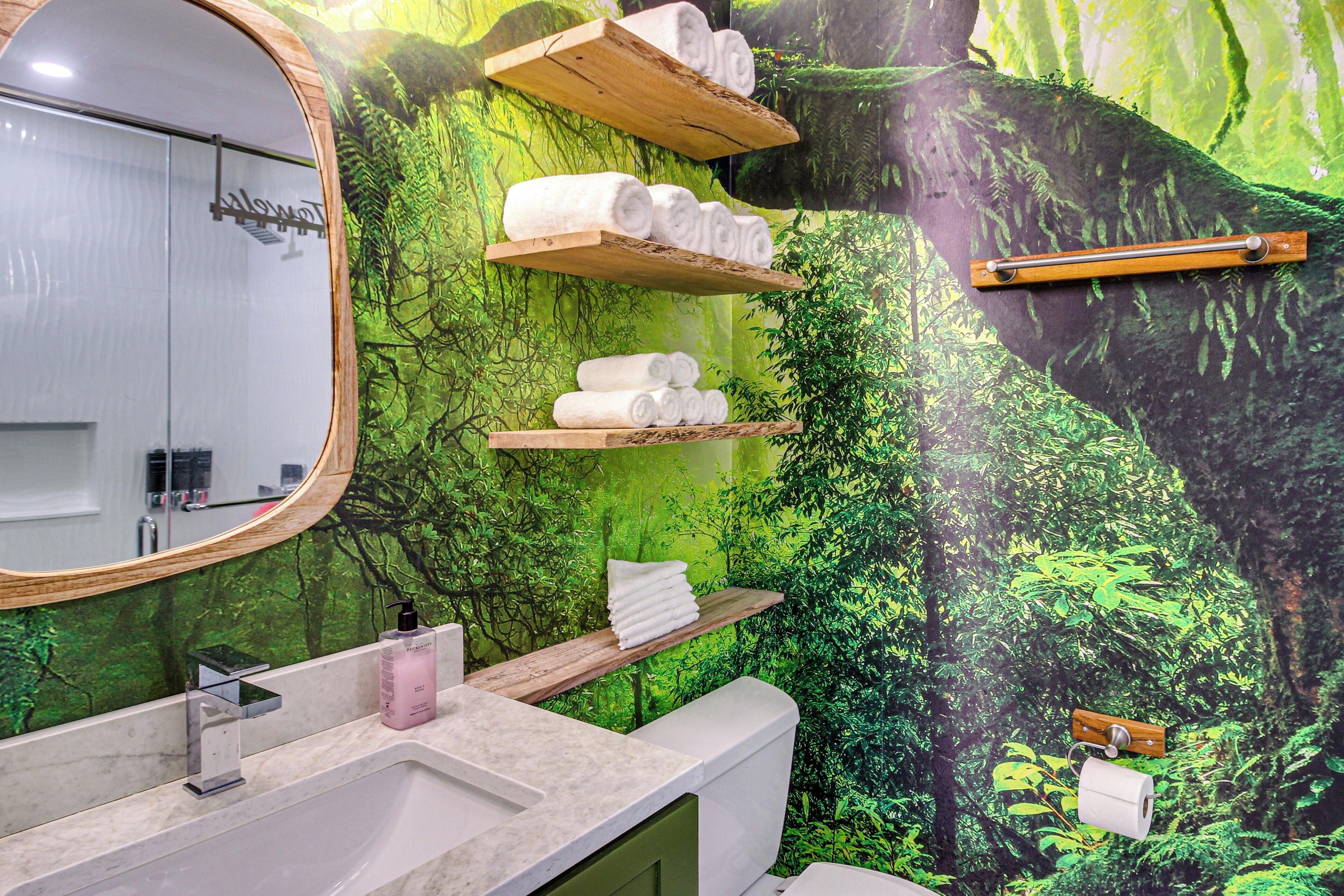 Une salle de bain avec un miroir, un lavabo et des étagères où sont rangées les serviettes.
