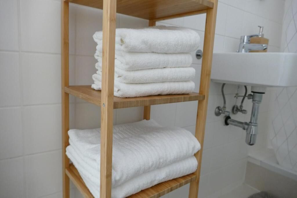 A wooden shelf with neatly folded white towels.