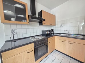 A modern kitchen with a stove, oven, and coffee maker.