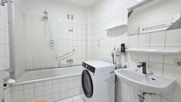 Ein modernes Badezimmer mit Dusche, Waschmaschine, Waschbecken und Toilette.