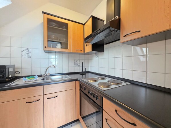 Una cocina moderna con armarios de madera, un lavamanos de acero inoxidable y una estufa a gas.