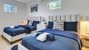 Een slaapkamer met twee bedden, een nachtkastje, een lamp en een schilderij aan de muur.