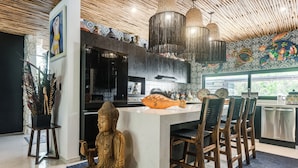Eine moderne Küche mit einer zentralen Kochinsel, Barhocker, einer Buddha-Statue und einem dekorativen Fisch.