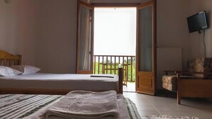 Een kamer met een bed, een televisie, een balkon en een stoel.