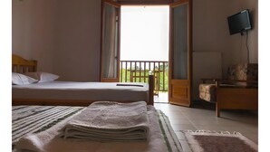 A room with a bed, a TV, a balcony, and a chair. - Studio Apartment 'Hotel Antigoni Triple Room 15' with Lake View, Wi-Fi and Air Conditioning (Neochori)