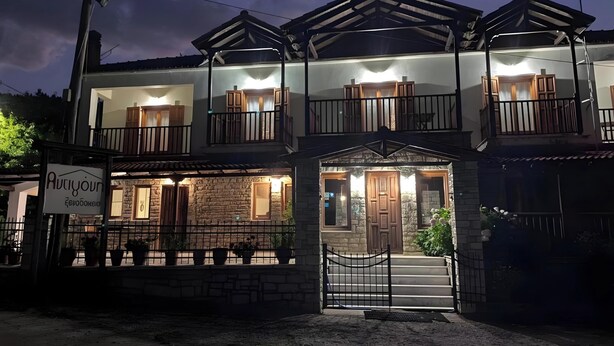 A two-story building with a stone facade, wooden balconies, and a signboard. - Studio Apartment 'Hotel Antigoni Triple Room 15' with Lake View, Wi-Fi and Air Conditioning (Neochori)