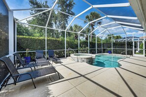 Ein überdachter Außenbereich mit Pool, Liegestühlen und Whirlpool.