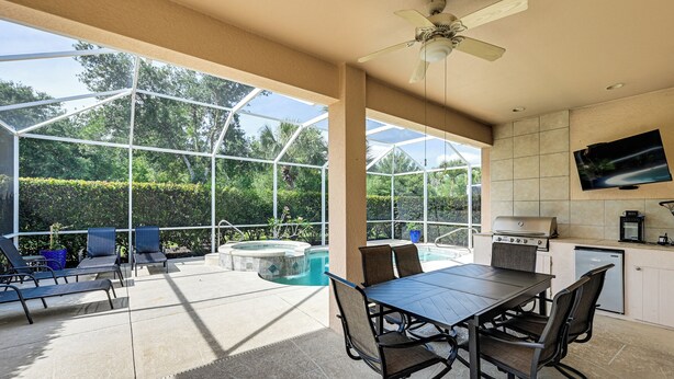 Un patio techado al aire libre con piscina, mesa de comedor, sillas y un ventilador de techo.