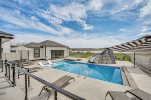 Ein Garten mit Swimmingpool, Liegestühlen und einem Steinelement.