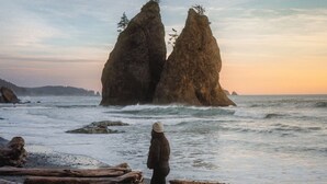 A person walking on a beach with large rock formations in the background. - 28-Acre Olympic Cabin · Hot Tub + Sauna · Private (Port Angeles)