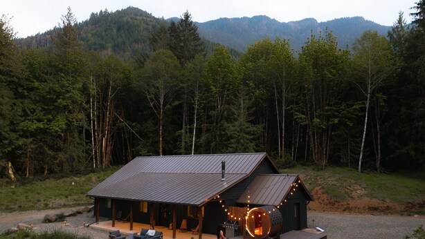 A cabin with a deck, outdoor seating, and a hot tub. - 28-Acre Olympic Cabin · Hot Tub + Sauna · Private (Port Angeles)