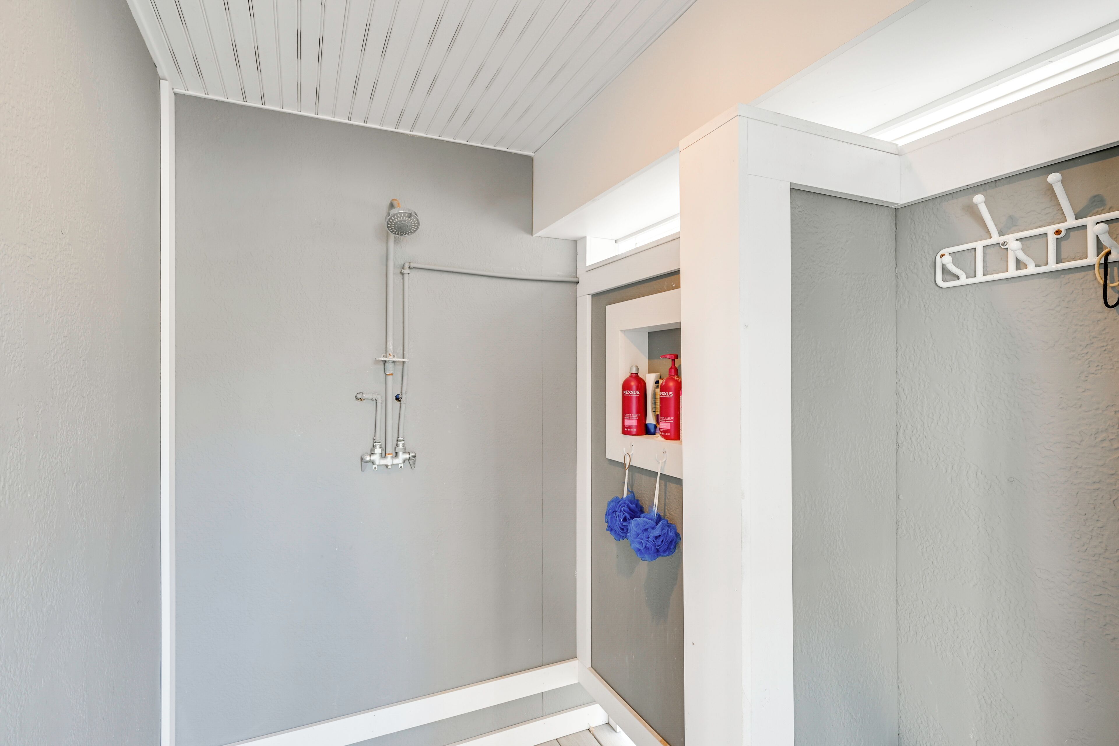 A bathroom with a shower, a towel rack, and a mirror.